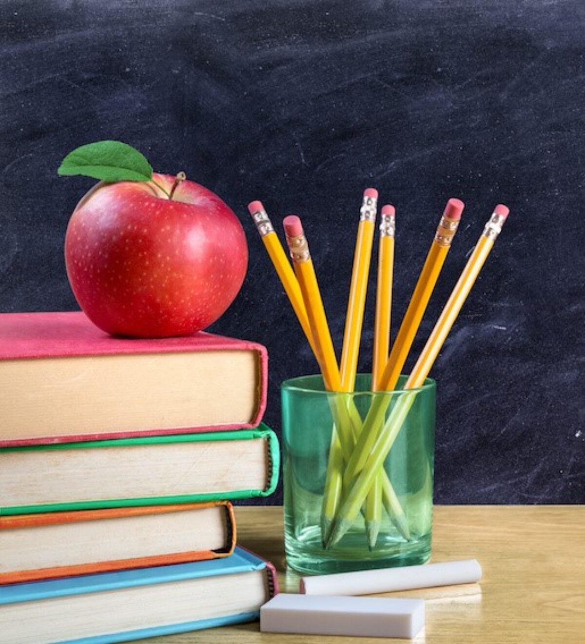 apple on books with pencils and empty blackboard - back to school