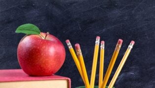 apple on books with pencils and empty blackboard - back to school